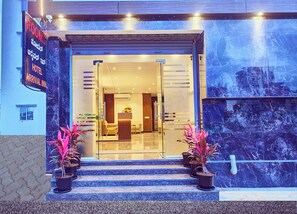 Vestíbulo de hotel con mostrador de recepción, zona de estar y escalones que llevan a la entrada.
