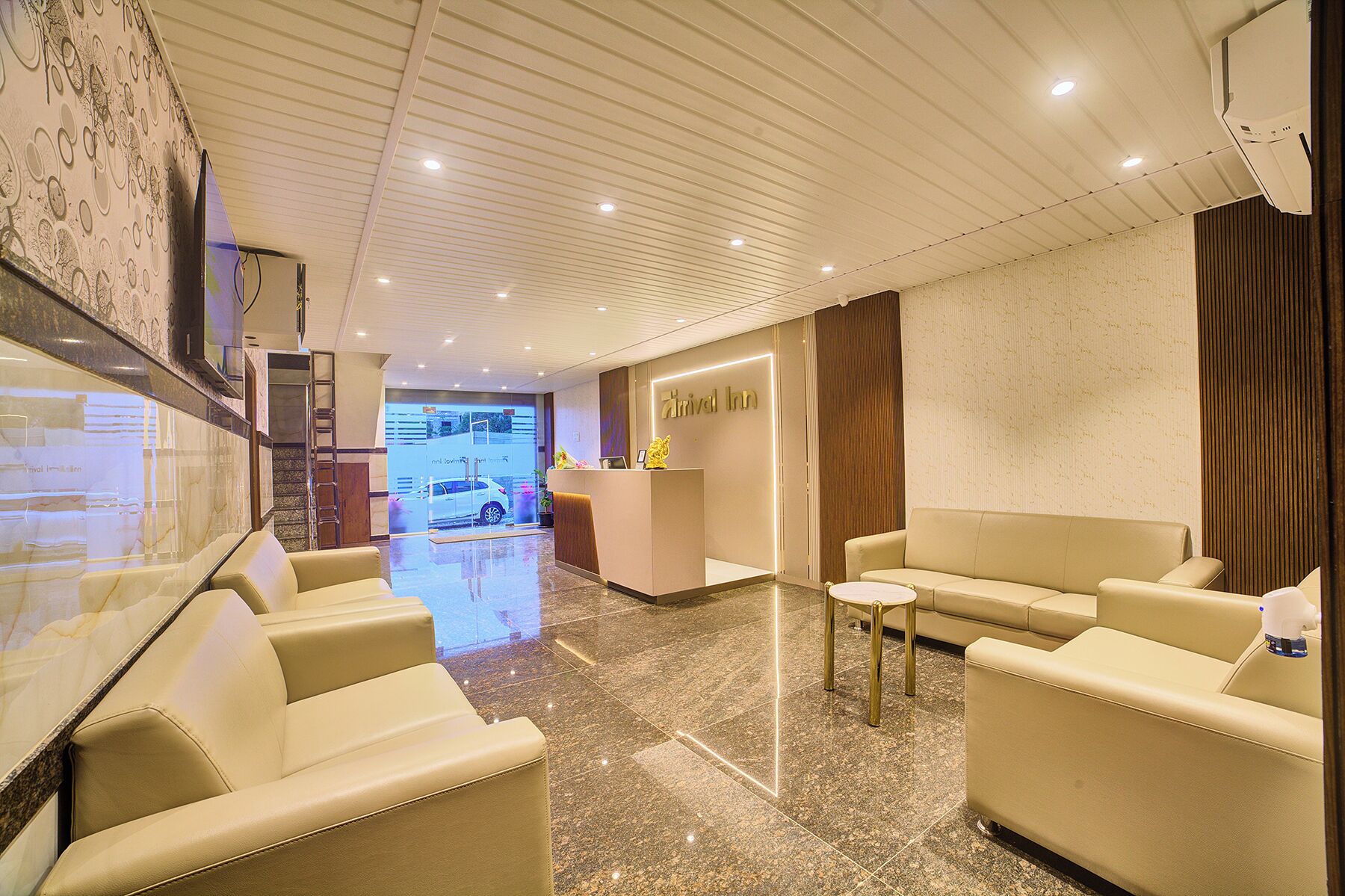 A hotel lobby with a reception desk, a waiting area with leather sofas, and a marble floor.
