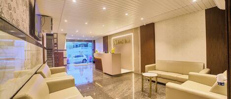 Una hall d'albergo con reception, zona d'attesa con divani in pelle e pavimento in marmo.
