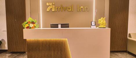 A reception desk with a sign reading "Arrival Inn" and a golden statue on the right.