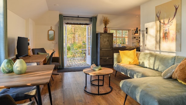 Un salon moderne avec une table à manger en bois, une table basse ronde, un canapé gris et un téléviseur.