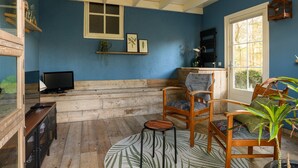 Une pièce avec un mur bleu, des bancs en bois, un téléviseur et une petite table.