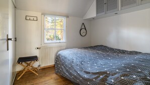 Une chambre à coucher avec un lit, un radiateur, une fenêtre et une porte.