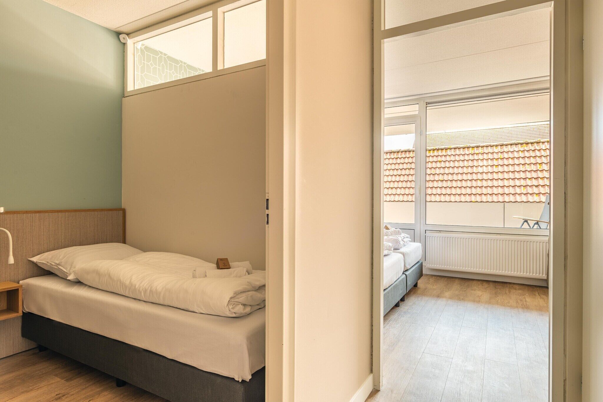 A bedroom with a bed, a nightstand, and a window with blinds.