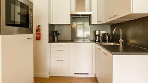 A compact kitchen with white cabinets, a stainless steel microwave, a gas stove, and a coffee maker. - Jungle-themed family escape (Bruinisse)