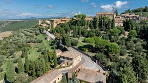 A hillside village with stone buildings, terraced fields, and a prominent church. - Maria Gabriella Cottage (Monticchiello)