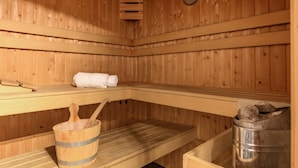 A sauna with wooden walls, a bench, a bucket, and a metal container. - Luxe 10-person family getaway (Bruinisse)