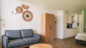 A modern living room with a grey sofa, a wooden cabinet, and a round wooden coffee table. - Spacious comfort stay for couple (Bruinisse)