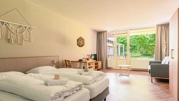A hotel room with two beds, a desk, a chair, a small table, and a sofa. - Spacious comfort stay for couple (Bruinisse)
