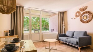 A modern living room with a grey sofa, a round wooden table, and a dining set. - Spacious comfort stay for couple (Bruinisse)