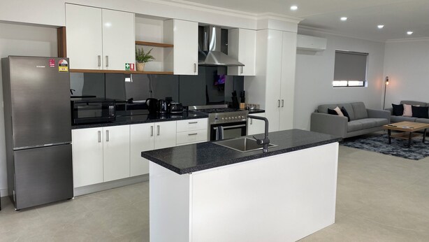 Una cocina moderna con armarios blancos, un refrigerador de acero inoxidable y una isla central.