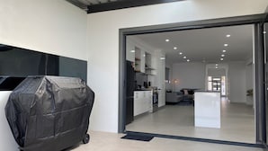 Una cocina moderna con armarios blancos, encimera negra y un ventanal corredero que da a un comedor.