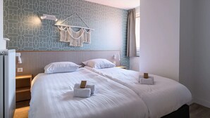 A hotel room with two beds, a geometric-patterned wall, macrame wall decor, and a bedside table with a lamp. - Modern apartment near centre facilities (Bruinisse)