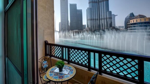 Un balcón con vistas a un horizonte urbano y una fuente de agua.