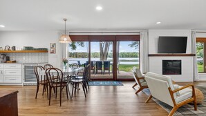 A modern kitchen with a dining area, a fireplace, and a large TV. - 4-Season Fun! Sandy Beach | Snowmobile Trails (Couderay)