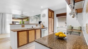 A modern kitchen with a central island, a built-in dishwasher, and a large window providing natural light.