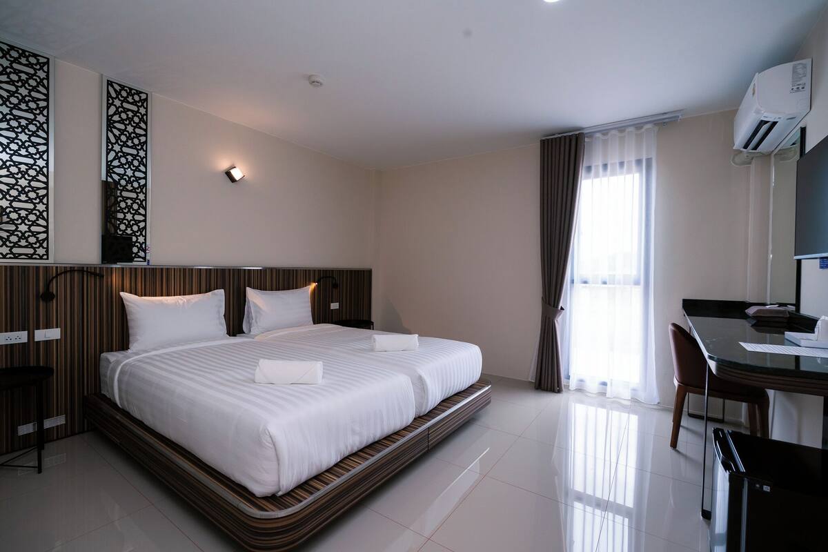 A modern hotel room with a large bed, a desk, and a chair.