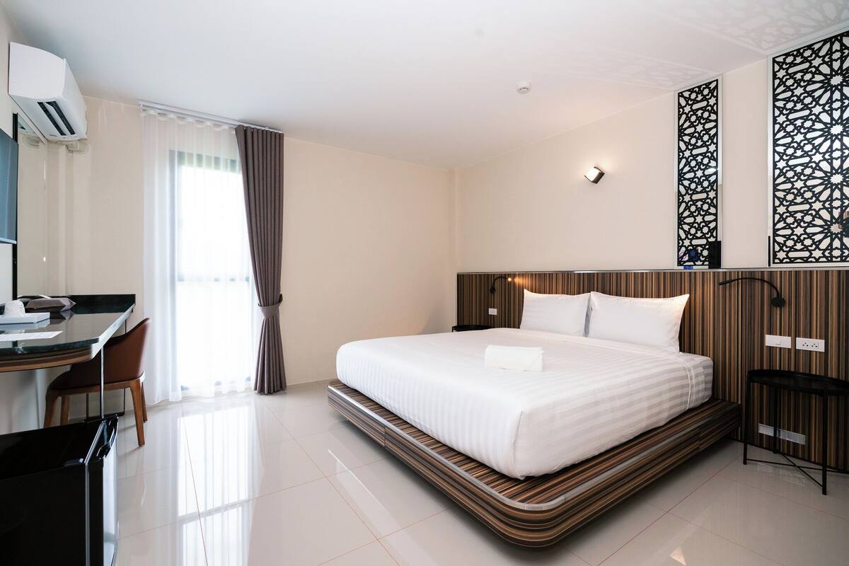 A modern hotel room with a large bed, a desk, and a chair.