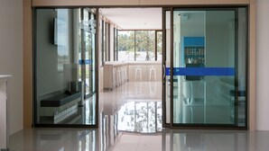 Un corridoio moderno di un hotel con porte in vetro, un pavimento piastrellato pulito e vista sull'esterno.