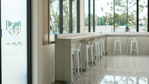 Zona bar moderna con una parete divisoria in vetro e sgabelli da bar bianchi.