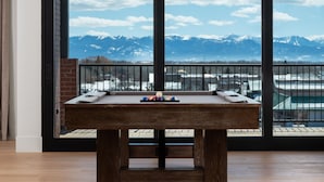 Une table de baby-foot dans une pièce dotée de grandes fenêtres donnant sur un paysage montagneux enneigé.