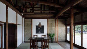 A traditional Japanese room with tatami flooring, a wooden table with chairs, a hanging lantern, and a large window with a view of the outside. - Renovated the main house of Maruyo Lumber, which is over 70 years old. Located in Funama-cho, Kuwana City, the site of the "Shichiri-no-watashi" ferry, the inn is a private house with antiques and artwork that blends the old and the new. (Semba cho, Kuwana city)