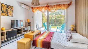 A modern bedroom with a bed, a TV, a desk, and a balcony with chairs. - Modern studio - AC - 2P - Cannes (Cannes)