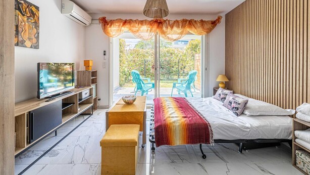 A modern bedroom with a bed, a TV, a dining table, and a view of the outdoors. - Modern studio - AC - 2P - Cannes (Cannes)