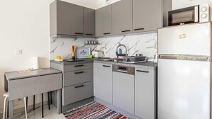 A modern kitchen with grey cabinets, a marble backsplash, a built-in dishwasher, and a refrigerator. - Modern studio - AC - 2P - Cannes (Cannes)