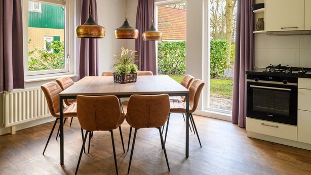 Une cuisine moderne avec un coin repas, de grandes fenêtres et une vue sur la verdure.