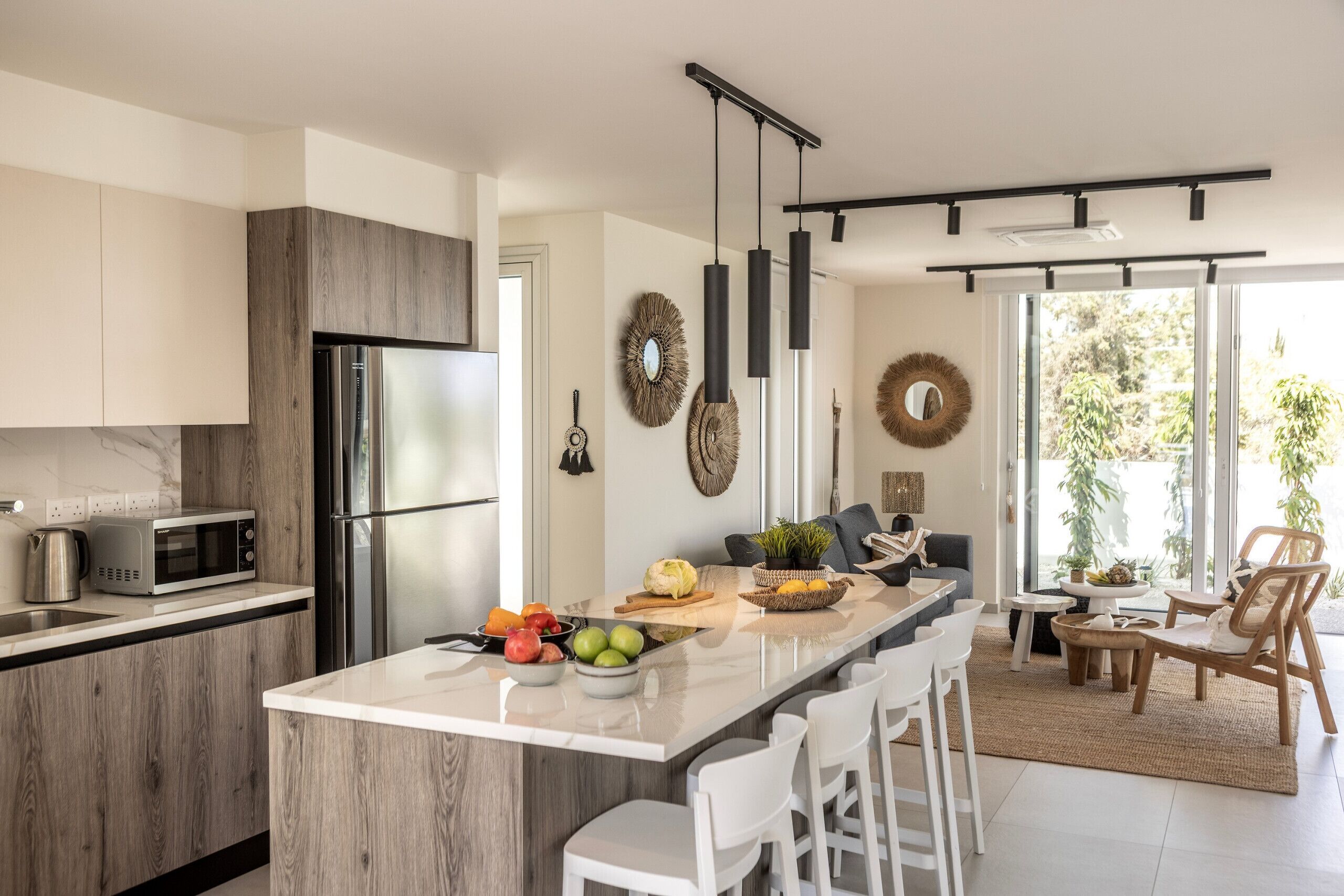 A modern kitchen with a central island, stainless steel appliances, and a dining area with a view of greenery.
