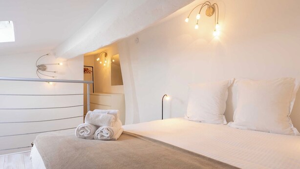 Ett hotellrum med en säng, en uppsättning handdukar och en väggmonterad lampa.