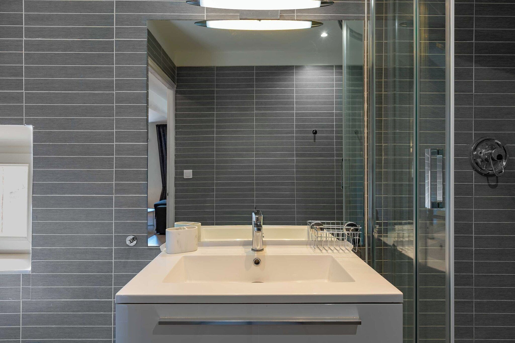 A modern bathroom with a large sink, a glass shower enclosure, and a mirror.