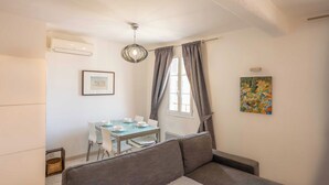 Ett kompakt bostadsutrymme med en matplats, en soffa och en takfläkt.