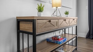 Une console en bois dotée de tiroirs et d’une étagère, agrémentée de plantes et d’une lampe.