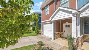 Une maison d’habitation avec un garage, des fondations en pierre et une pelouse bien entretenue.