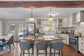A modern kitchen with a central island, stainless steel appliances, and pendant lighting.