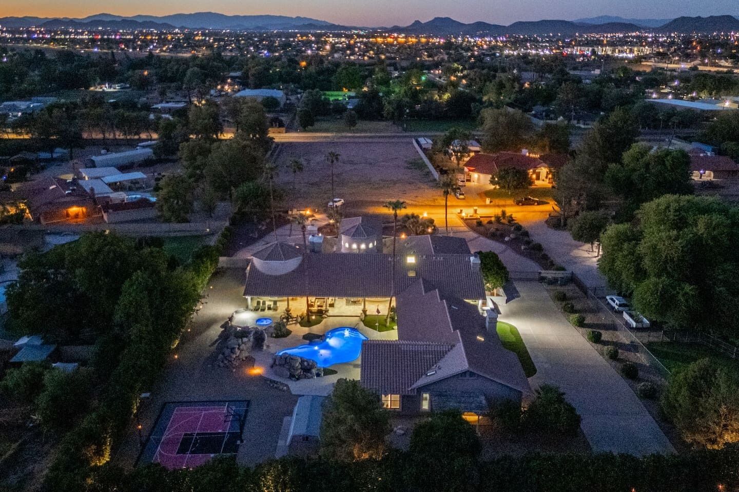 A residential property with a swimming pool, tennis court, and a large driveway.