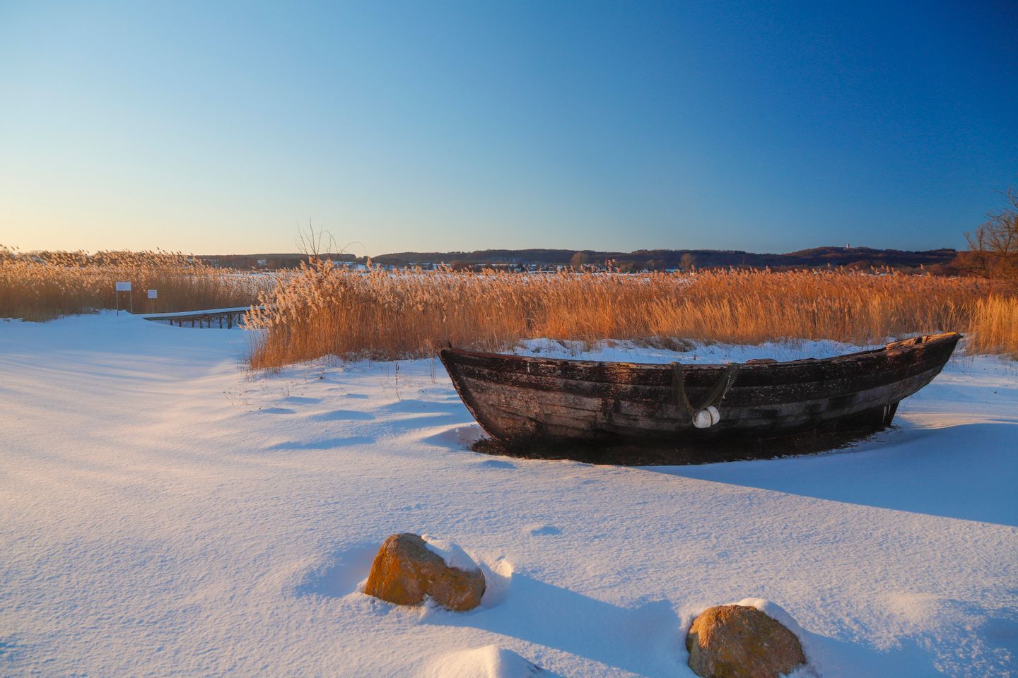 A boat in a snowy field with a clear sky.