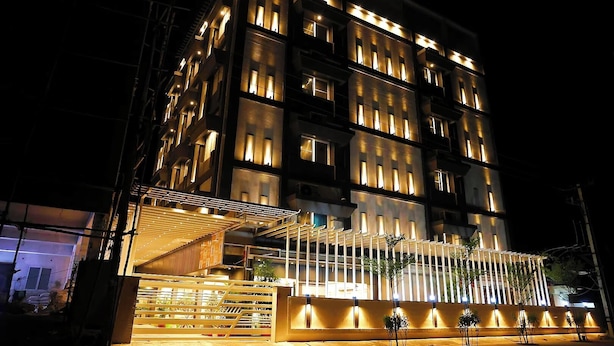 Un hotel de varios pisos con un diseño moderno, que cuenta con balcones y un área de entrada cubierta.