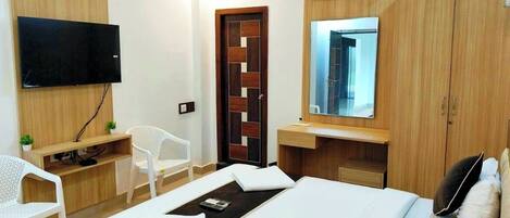 Ein Hotelzimmer mit Bett, Fernseher, Schreibtisch, Stuhl und Kleiderschrank.