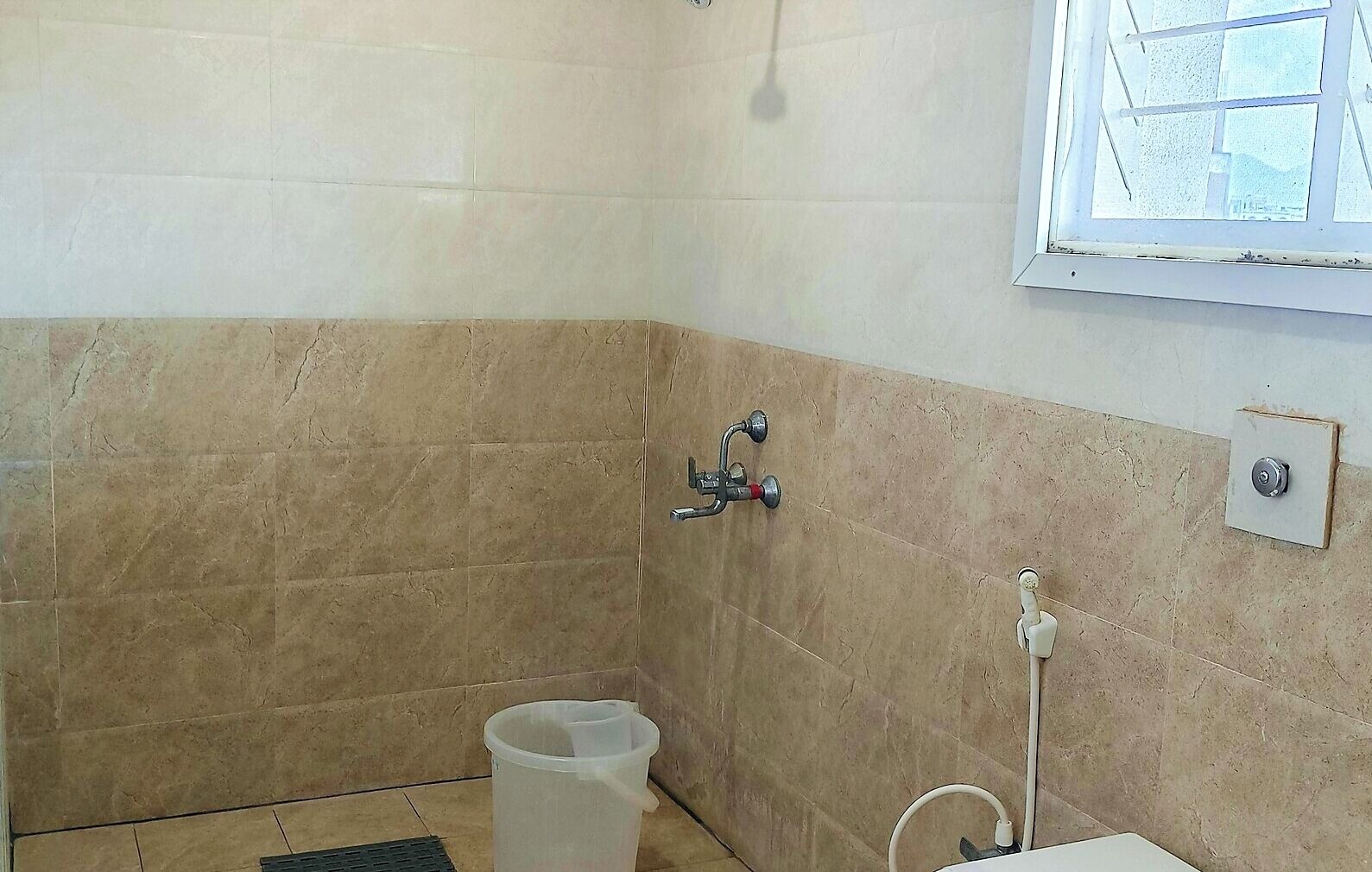 A small bathroom with a shower, a toilet, and a window.