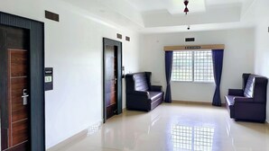 Habitación amplia con un ventanal grande, dos sofás de cuero oscuro, un ventilador de techo y un cartel de 'No Smoking'.