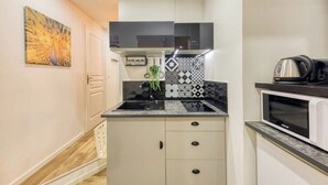 Une cuisine de taille réduite, dotée d’un plan de travail noir, d’un four à micro-ondes et d’une cuisinière.