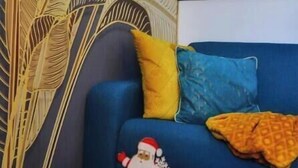 Une pièce avec un canapé bleu, une table basse en bois et un panneau décoratif mural.