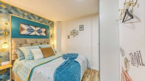 Une chambre à coucher comprenant un lit, une tête de lit, une lampe fixée au mur et un élément décoratif mural.