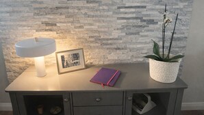 A desk with a white sink, a framed picture, a purple notebook, and a potted plant against a textured wall.
