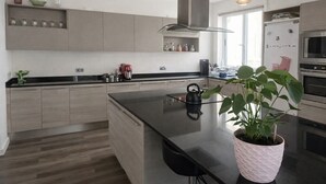 A modern kitchen with a central island, stainless steel appliances, and a potted plant.