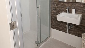 A modern bathroom with a glass shower enclosure, a white sink, and a mirror above it. - Ensuite Twin + Laundry, Pembroke (Pembroke)