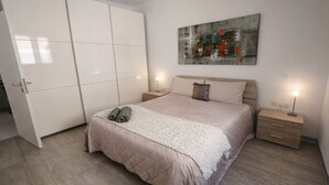 A bedroom with a bed, a wardrobe, a nightstand, and a painting on the wall. - Cozy Double Room in Pembroke (Pembroke)